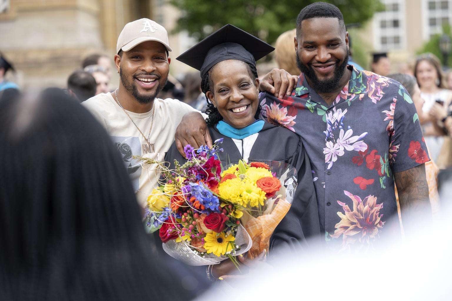 A graduate poses with her family while holding flowers