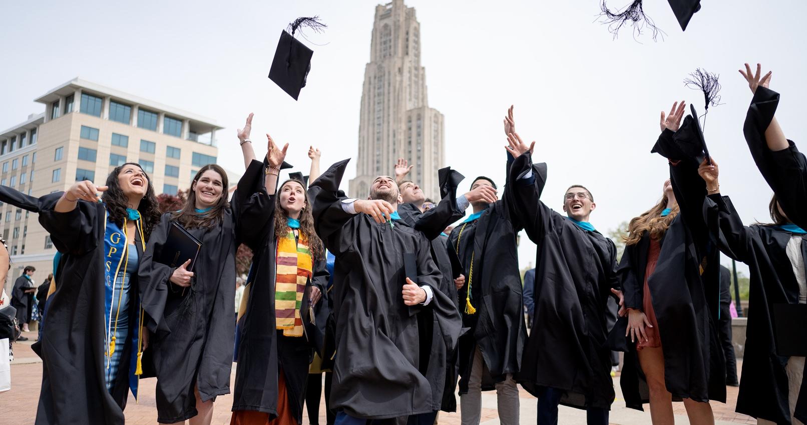 Proud SPIA graduates tossing their graduation caps